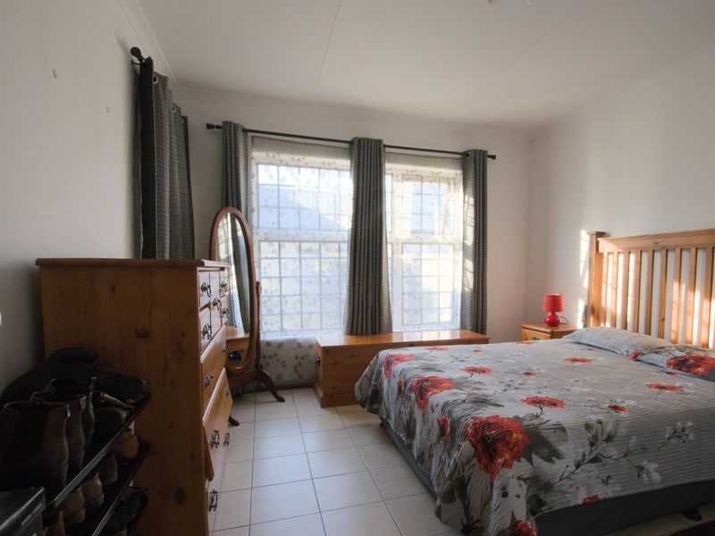 A functional bedroom featuring tiled flooring and large windows with curtain rails, providing natural light and a neutral foundation for interior design.