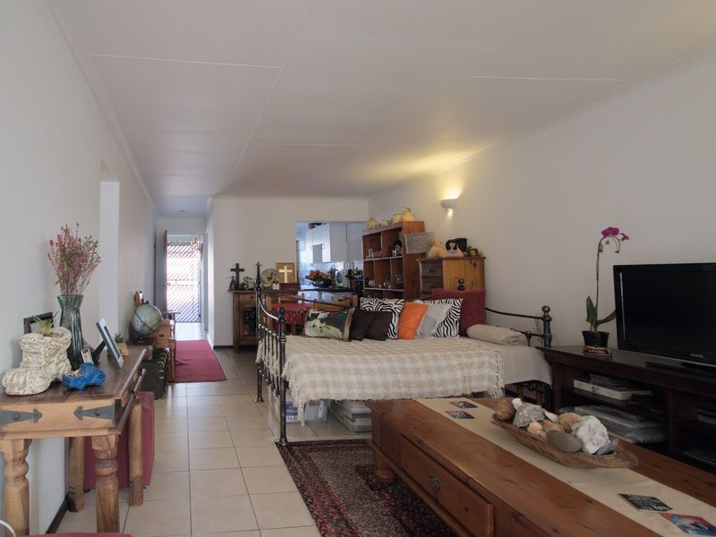 An open-plan living area featuring tiled flooring and neutral walls, providing a functional space that flows towards the kitchen and rear entrance.