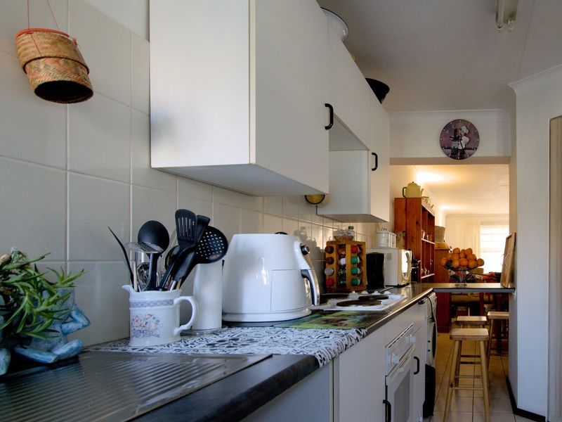 A functional kitchen featuring white cabinetry, tiled backsplash, and built-in cooking appliances, leading into an adjacent living area.