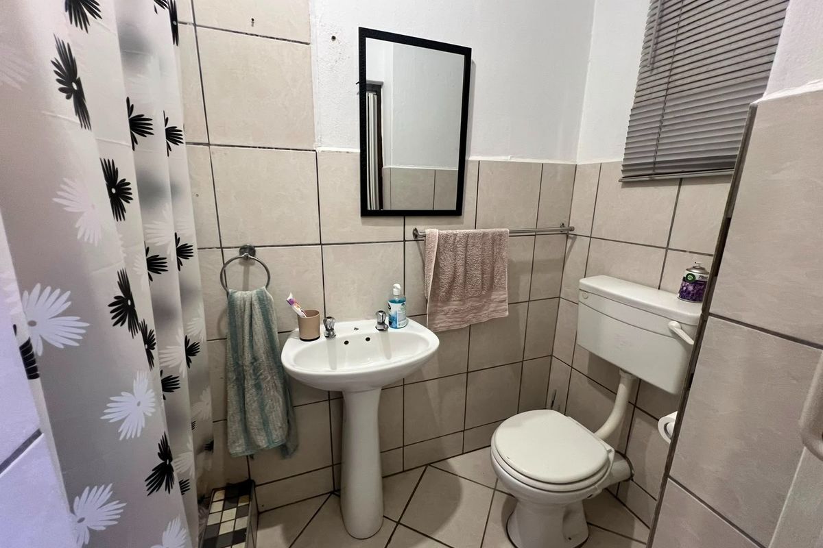 Compact bathroom featuring a pedestal basin, toilet, and tiled finishes. The space is functional but would benefit from cosmetic updates and modern fixtures.