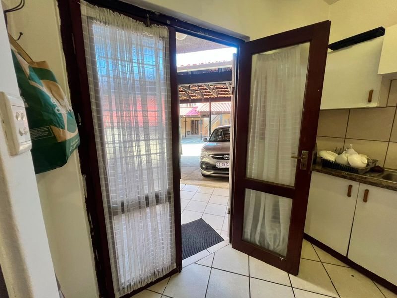 Entryway leading to an outdoor parking area, featuring tiled flooring and direct access to the kitchen space.