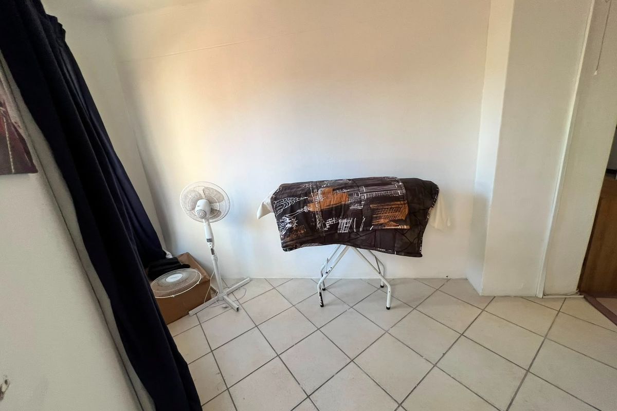 A simple, tiled bedroom space with plain white walls, suitable for a variety of interior design styles.