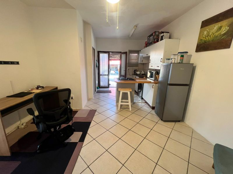 Open-plan living and kitchen area featuring tiled flooring, built-in cabinetry, and direct access to the exterior through a glass panel door.