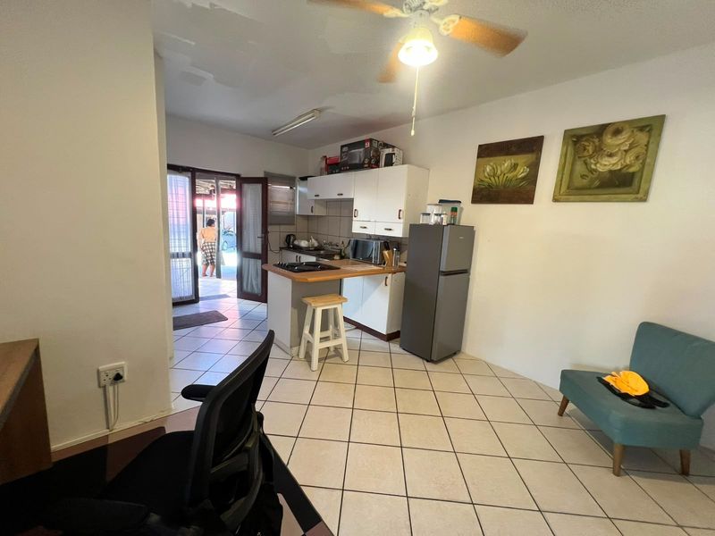 Open plan kitchen and living area featuring tiled flooring, built-in cabinetry, and direct access to an outdoor patio area.