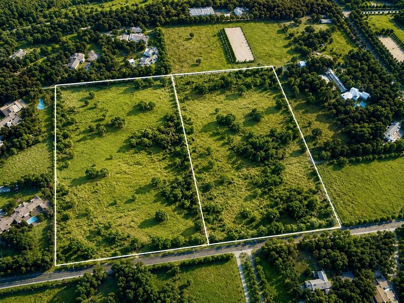 An aerial view of a large, undeveloped residential land parcel with clear boundary lines, situated in a green, established neighborhood.