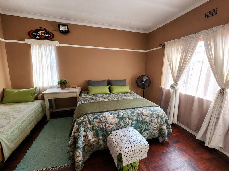 A bedroom featuring traditional parquet flooring, cornicing, and security bars on the windows, offering a functional space with potential for cosmetic updates.