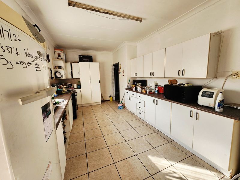 A functional kitchen featuring extensive built-in cabinetry, laminate countertops, and ceramic tiled flooring, offering a practical layout with ample storage space.