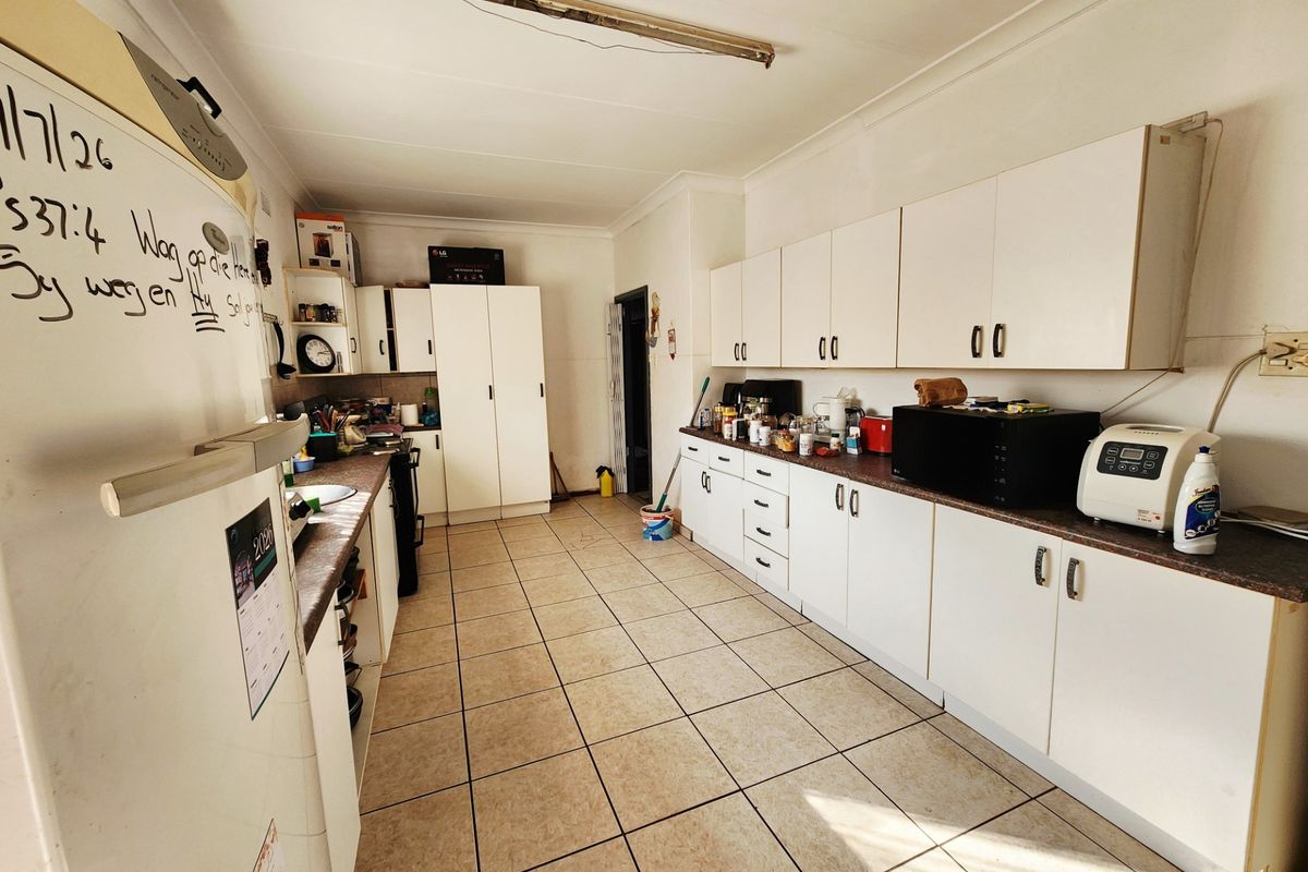 A functional kitchen featuring extensive built-in cabinetry, laminate countertops, and ceramic tiled flooring, offering a practical layout with ample storage space.