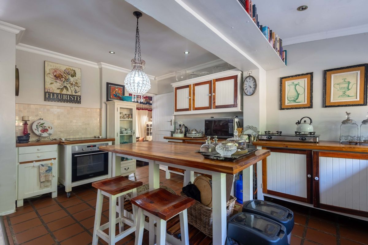 A functional kitchen featuring wooden countertops, built-in oven, cooktop, tiled backsplash, and cabinetry, with a central island and tiled flooring.