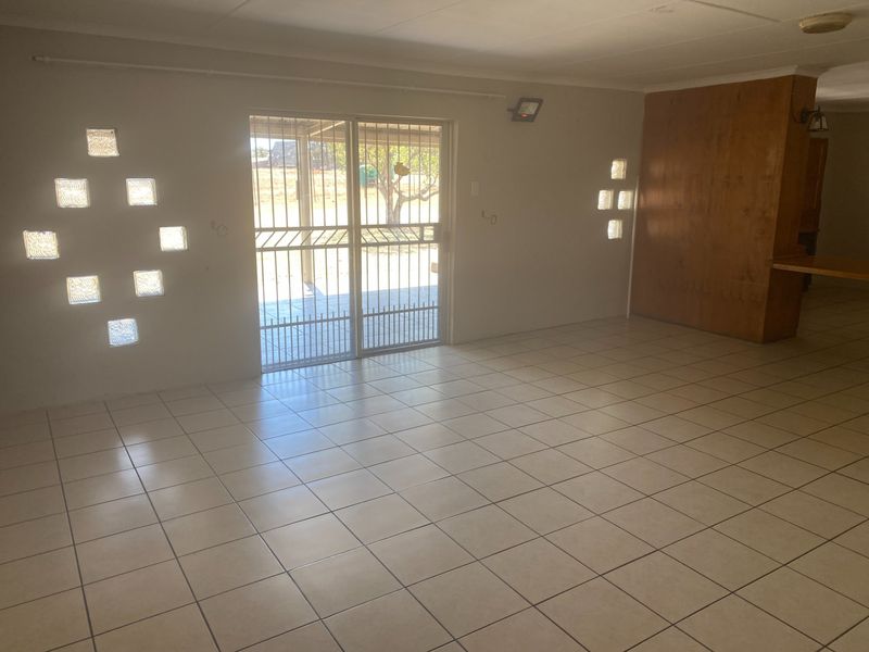 Spacious living area featuring ceramic floor tiles, unique glass block windows, and a sliding door leading to the exterior.
