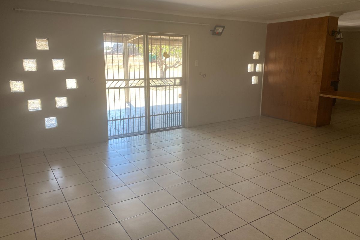 Spacious living area featuring ceramic floor tiles, unique glass block windows, and a sliding door leading to the exterior.