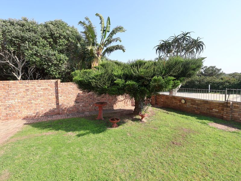 A well-maintained private garden featuring a manicured lawn, mature landscaping, and secure brick boundary walls with metal fencing.