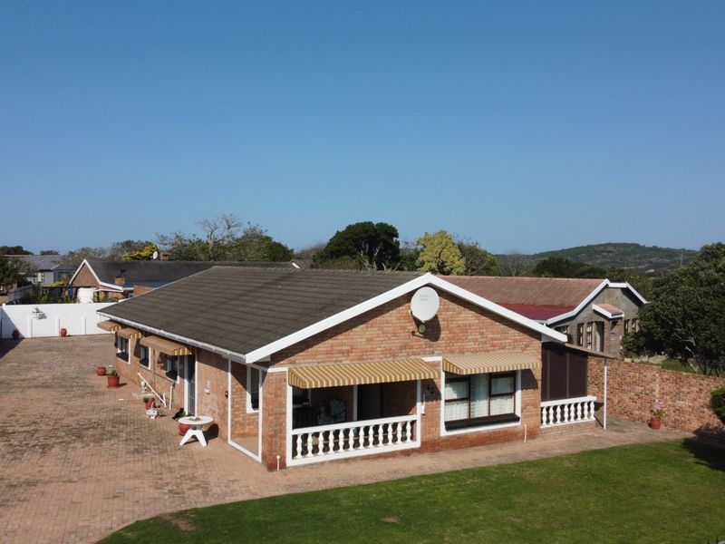 Aerial view of a single-story brick house featuring a large paved driveway, tiled roof, and a covered patio area with balustrades.