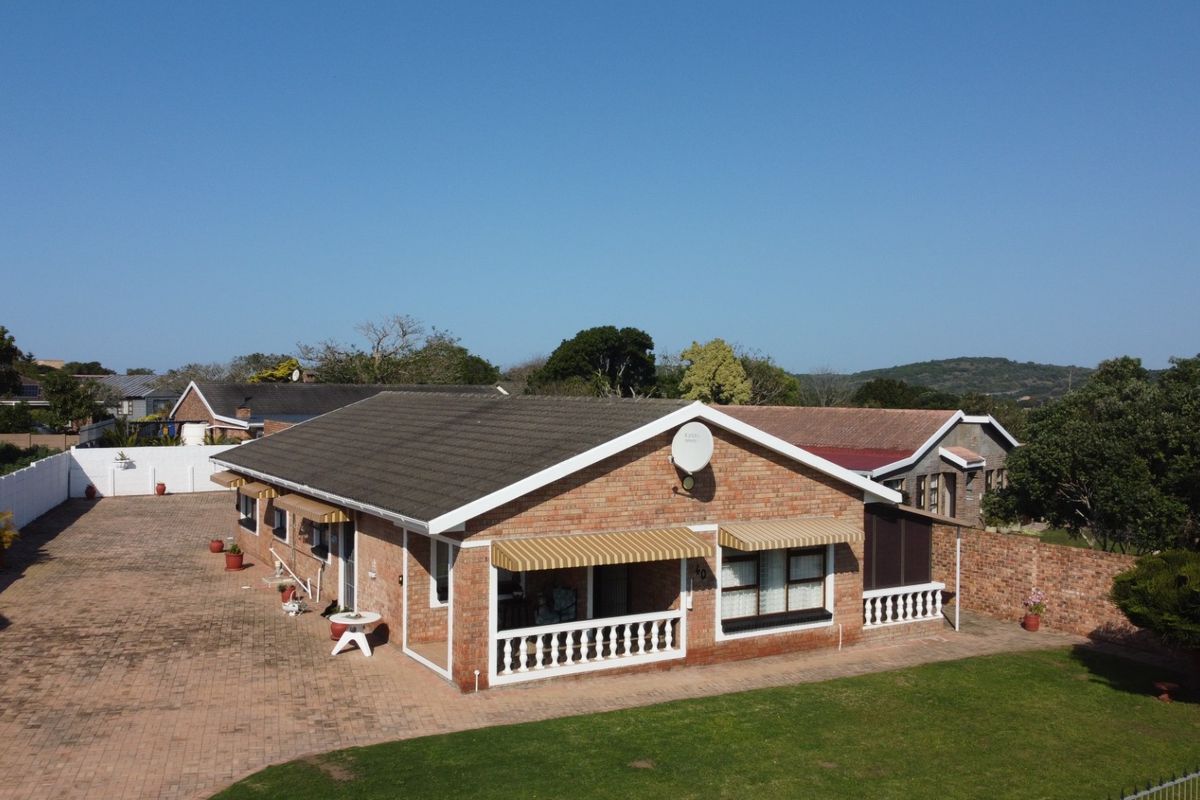 Aerial view of a single-story brick house featuring a large paved driveway, tiled roof, and a covered patio area with balustrades.
