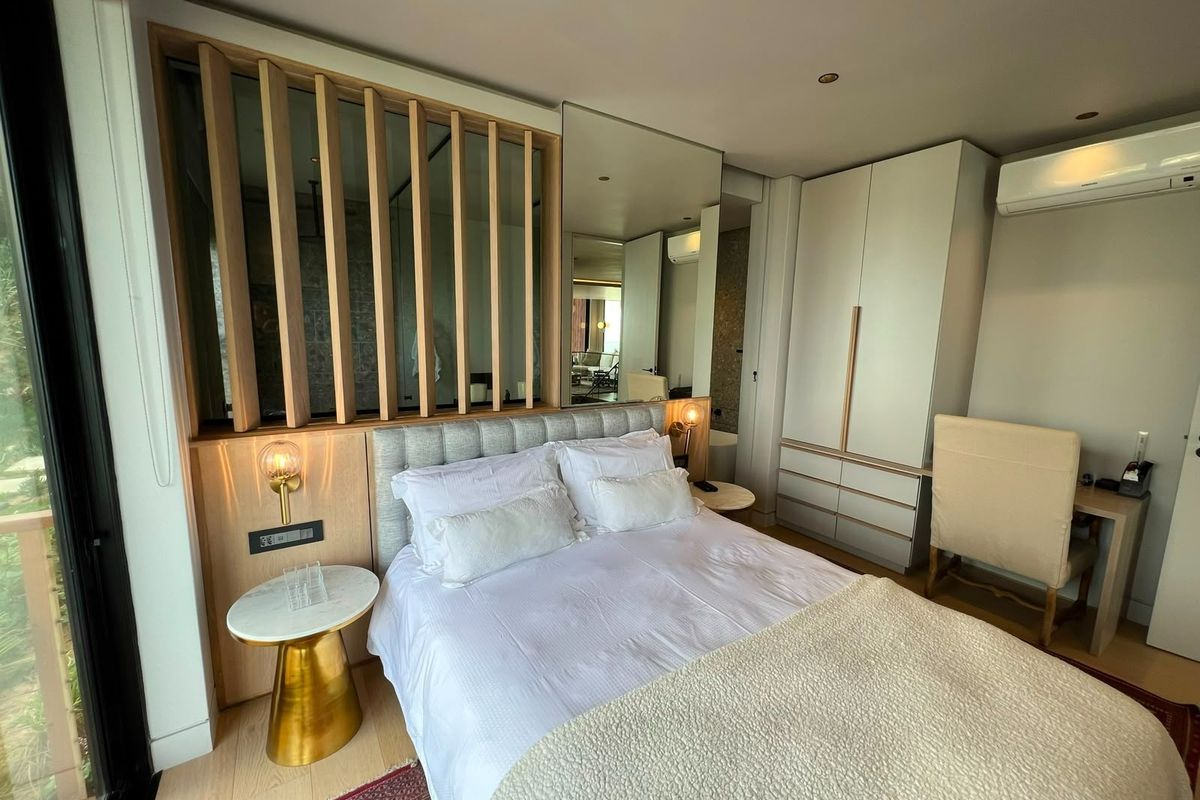 Modern bedroom featuring timber slat detailing, built-in cabinetry, integrated desk space, and wall-mounted air conditioning, offering a clean and contemporary aesthetic.