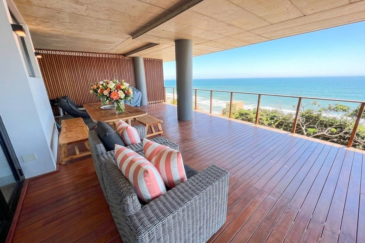 Spacious covered balcony featuring high-quality timber decking, modern glass balustrades, and stunning panoramic ocean views, perfect for outdoor relaxation.
