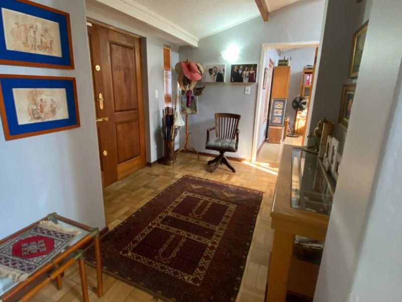 Entrance foyer featuring classic parquet flooring, a solid wood front door, and an exposed ceiling beam, leading into the home's interior living spaces.