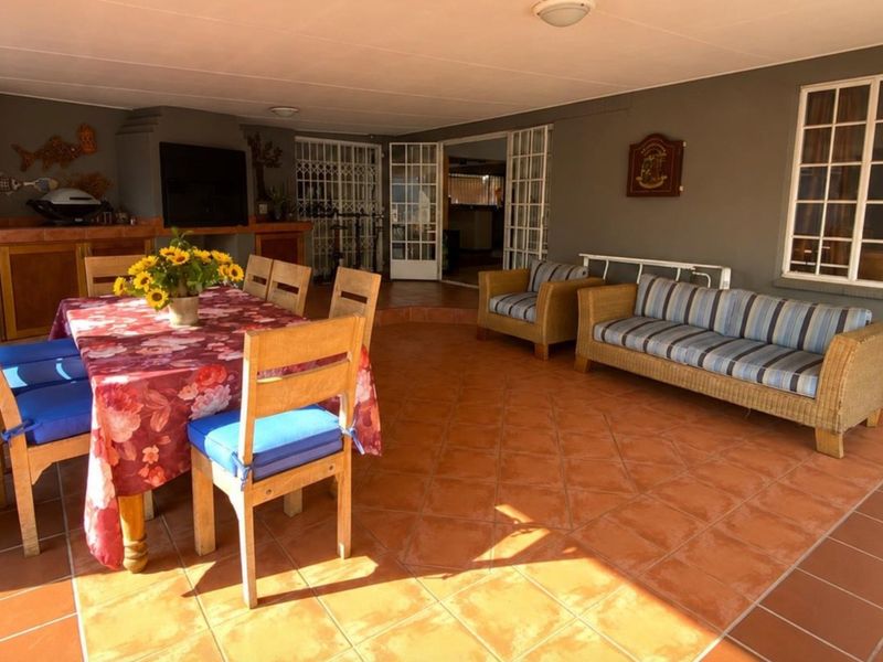 Covered outdoor patio area featuring terracotta tiled flooring and a built-in braai, providing a functional space for outdoor dining and relaxation.
