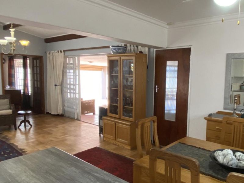 Spacious open-plan living and dining area featuring parquet flooring, coved ceilings, and sliding glass doors leading to an outdoor patio space.