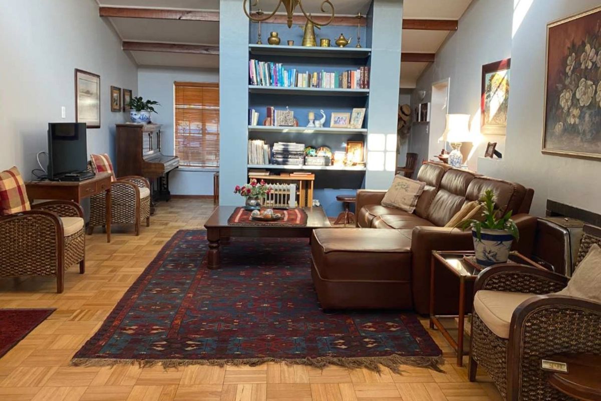 Spacious living room featuring classic parquet flooring, exposed ceiling beams, and a central built-in shelving unit, creating a warm and inviting atmosphere.