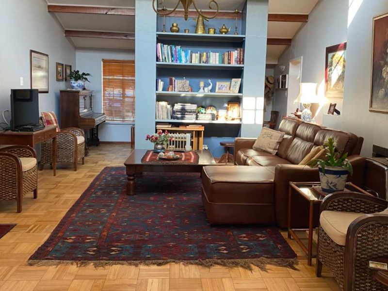 Spacious living room featuring classic parquet flooring, exposed ceiling beams, and a central built-in shelving unit, creating a warm and inviting atmosphere.