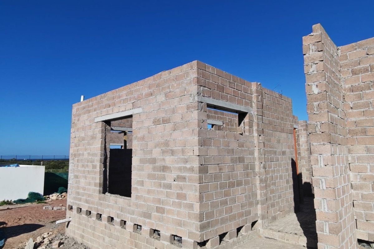 A property under construction featuring exposed concrete block masonry walls and structural lintels, representing the early stages of building development.