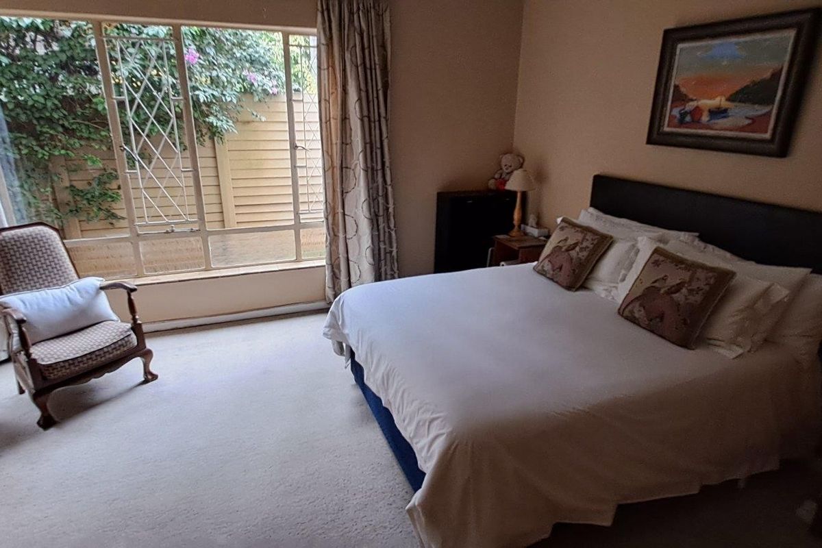 A spacious bedroom featuring large windows that provide natural light and views of the garden area.