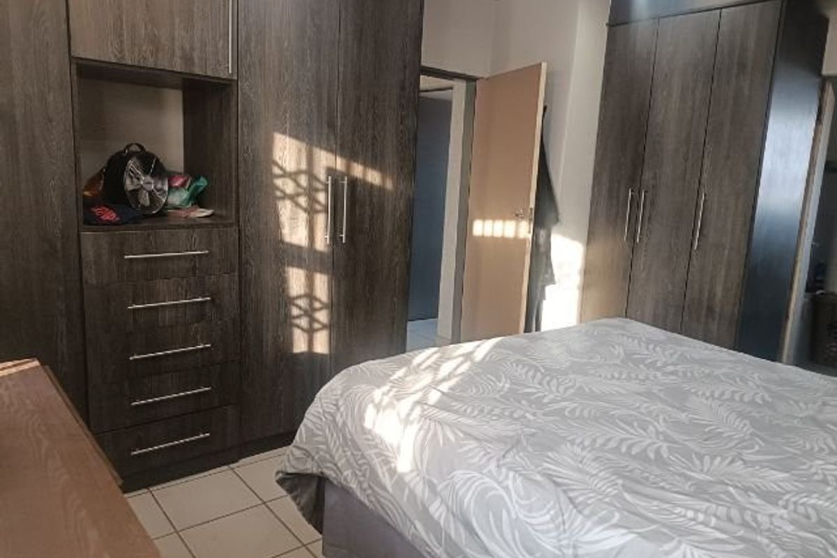 A bedroom featuring extensive dark wood built-in cupboards and tiled flooring, providing ample storage space.