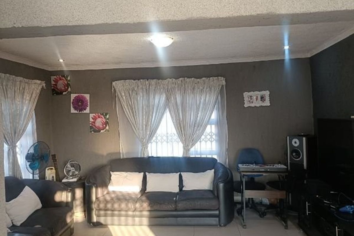 A living room featuring tiled flooring, recessed downlighting, and security gates on the windows, providing a functional and lived-in space.