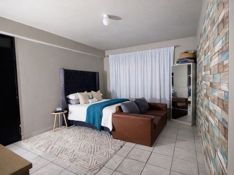 A bedroom featuring tiled flooring and a decorative feature wall, providing a functional space with neutral wall tones.