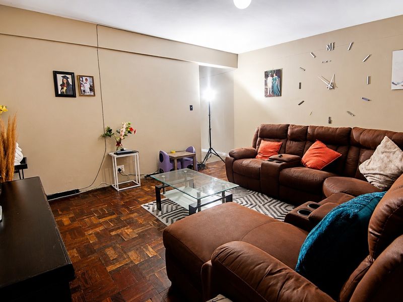 A living room featuring traditional parquet flooring and neutral wall tones, offering a functional space for relaxation.