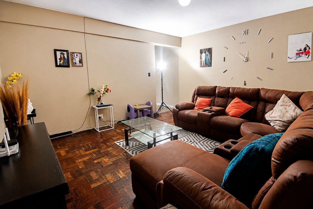 A living room featuring traditional parquet flooring and neutral wall tones, offering a functional space for relaxation.
