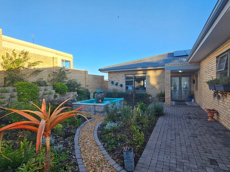 A well-maintained front entrance featuring a paved walkway, landscaped garden with a water feature, and a classic brick facade.
