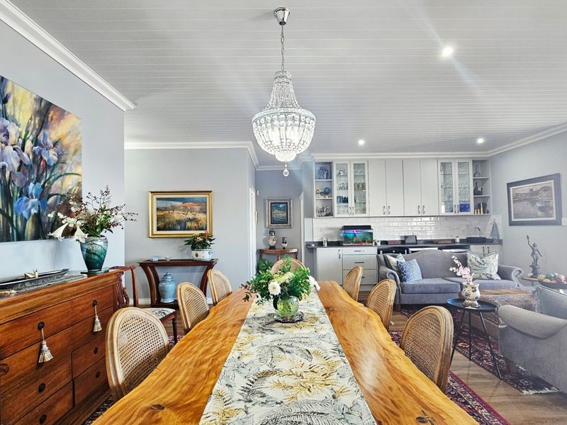 Spacious open-plan living and dining area featuring a beaded timber ceiling, elegant crystal chandelier, and a well-appointed kitchen with classic cabinetry.
