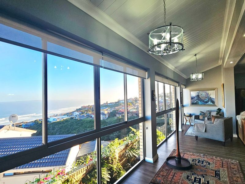 Spacious living area featuring expansive floor-to-ceiling windows with panoramic coastal views, high-quality finishes, and a bright, airy atmosphere.