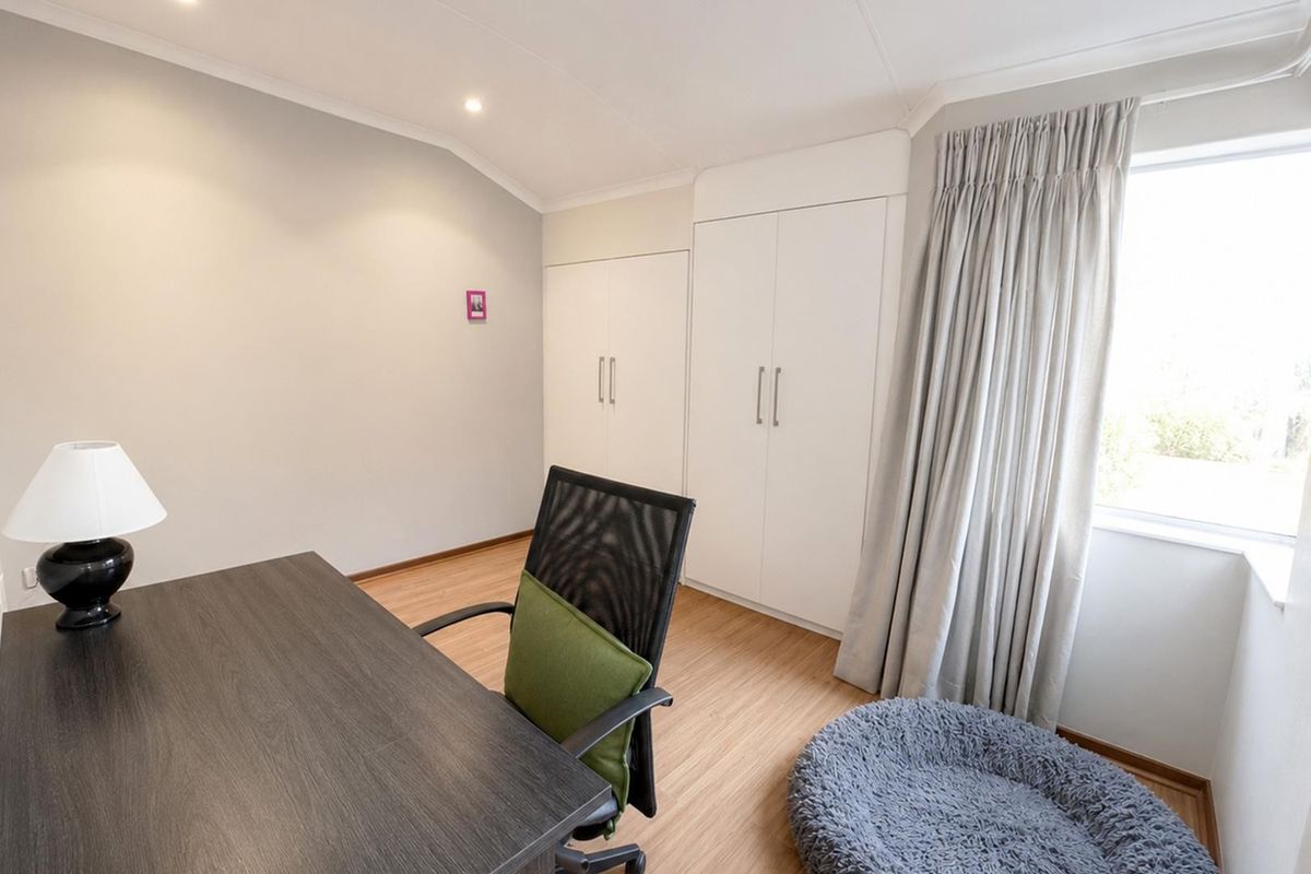 A well-maintained bedroom featuring neutral walls, laminate flooring, and ample built-in cupboard storage, offering a clean and functional living space.