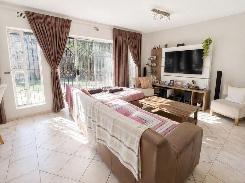 A bright living room featuring tiled flooring and large sliding glass doors that provide direct access to the outdoor area.