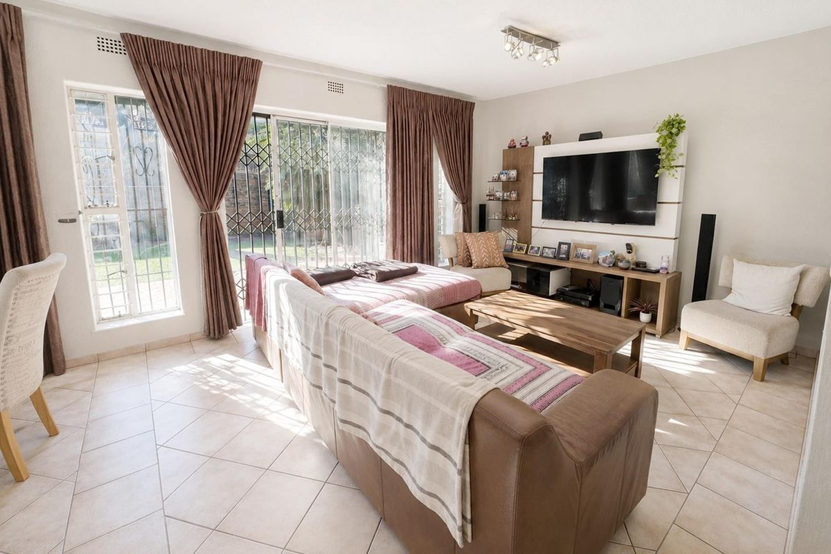 A bright living room featuring tiled flooring and large sliding glass doors that provide direct access to the outdoor area.