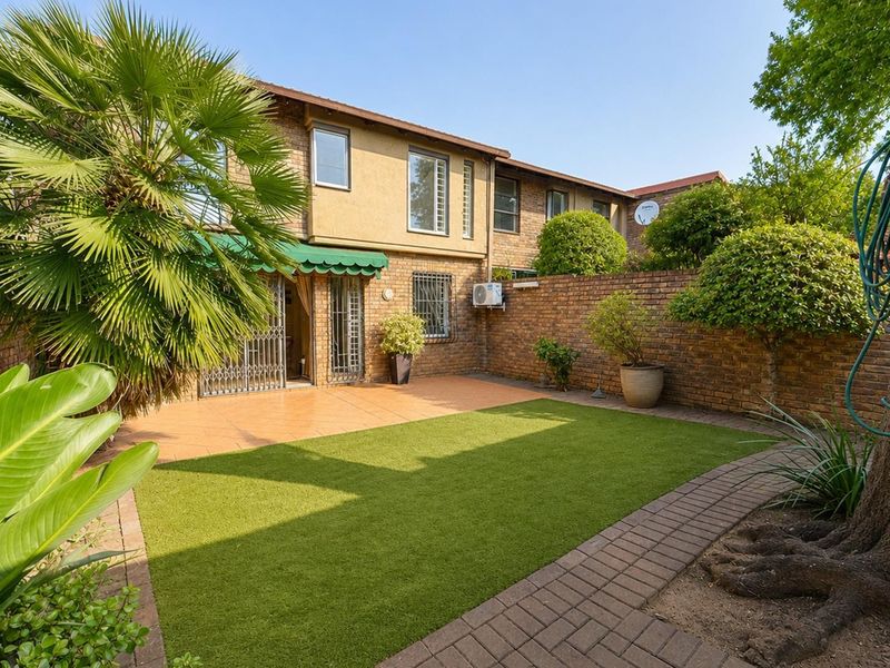 A private rear garden featuring a paved patio area, artificial lawn, and brick boundary walls, providing a low-maintenance outdoor space.