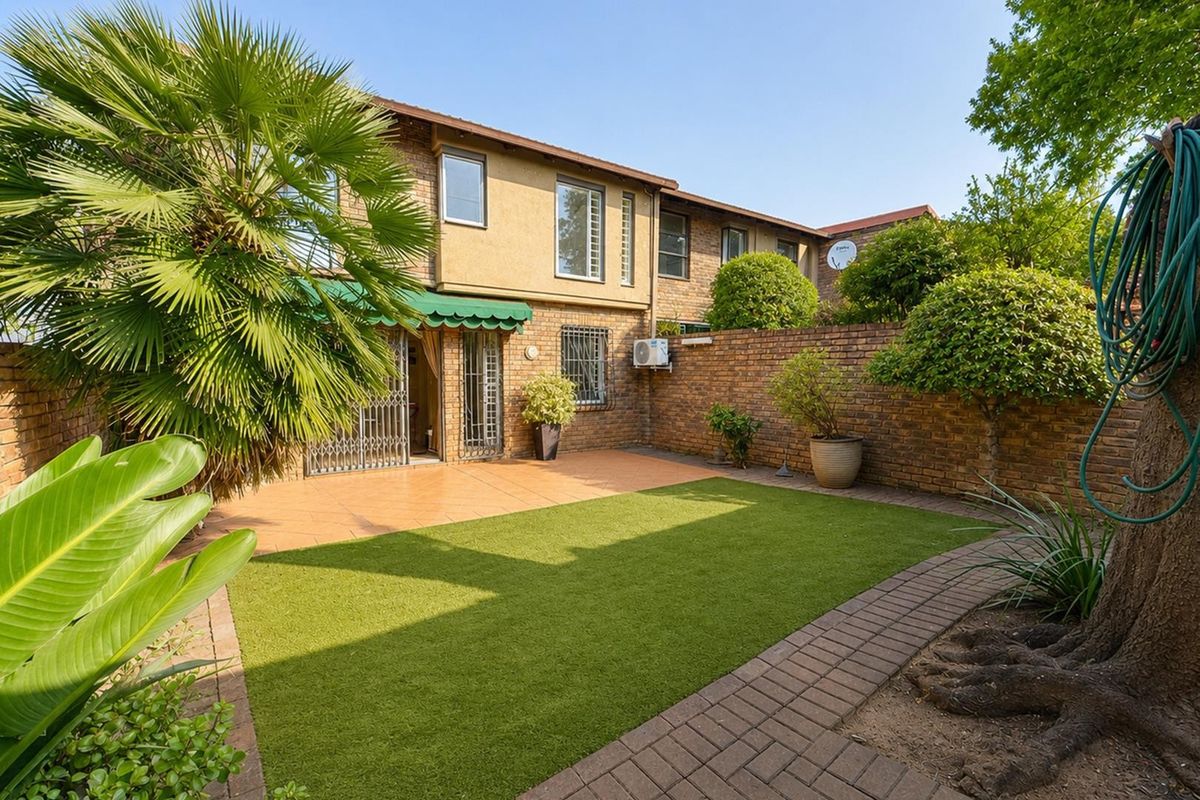 A private rear garden featuring a paved patio area, artificial lawn, and brick boundary walls, providing a low-maintenance outdoor space.