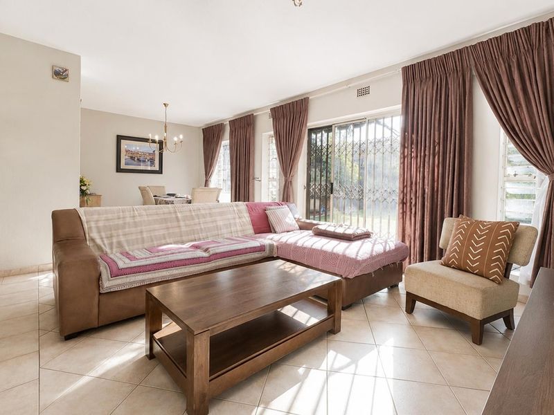 Spacious open-plan living and dining area featuring ceramic tiled flooring and large sliding glass doors with security gates leading to the exterior.