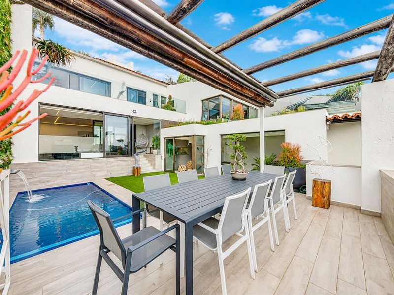 Modern outdoor entertainment area featuring a timber pergola, tiled patio, and a sleek plunge pool with a built-in water feature.