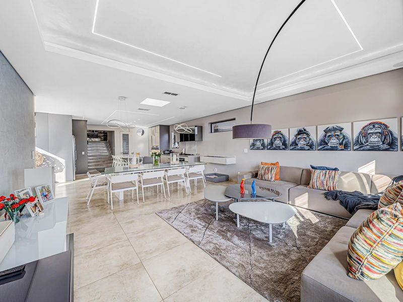 Spacious open-plan living and dining area featuring modern tiled floors, recessed ceiling lighting, a skylight, and a seamless transition to the kitchen and staircase.