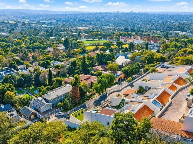 An elevated aerial view of the townhouse complex, showcasing the surrounding neighborhood, roof structures, solar installations, and landscaped grounds.