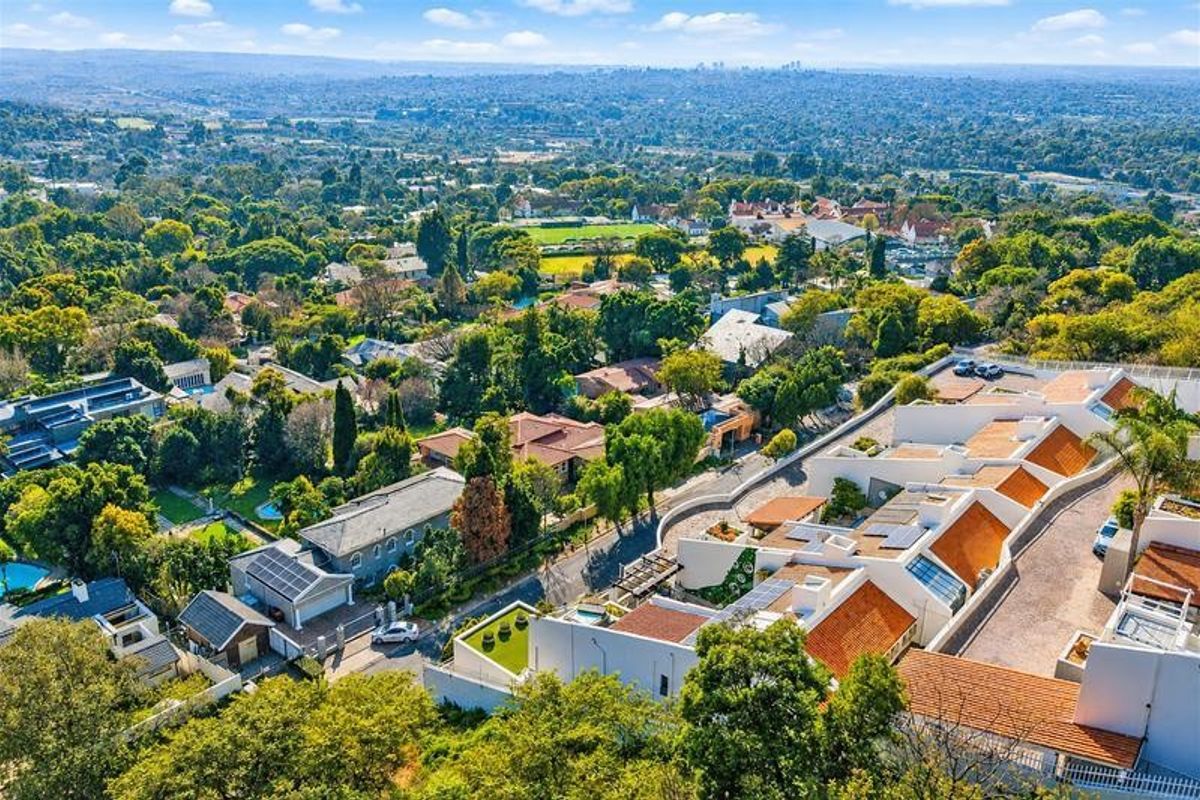 An elevated aerial view of the townhouse complex, showcasing the surrounding neighborhood, roof structures, solar installations, and landscaped grounds.
