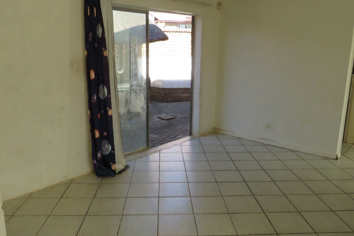 An empty living room featuring ceramic floor tiles and a sliding glass door providing access to the outdoor area.