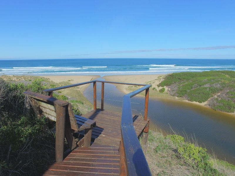 A scenic elevated timber viewing deck overlooking a coastal estuary and the ocean, providing a peaceful vantage point.