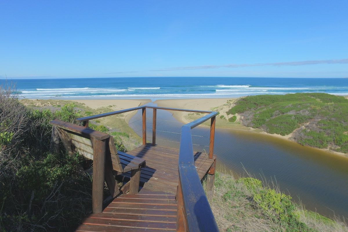 A scenic elevated timber viewing deck overlooking a coastal estuary and the ocean, providing a peaceful vantage point.