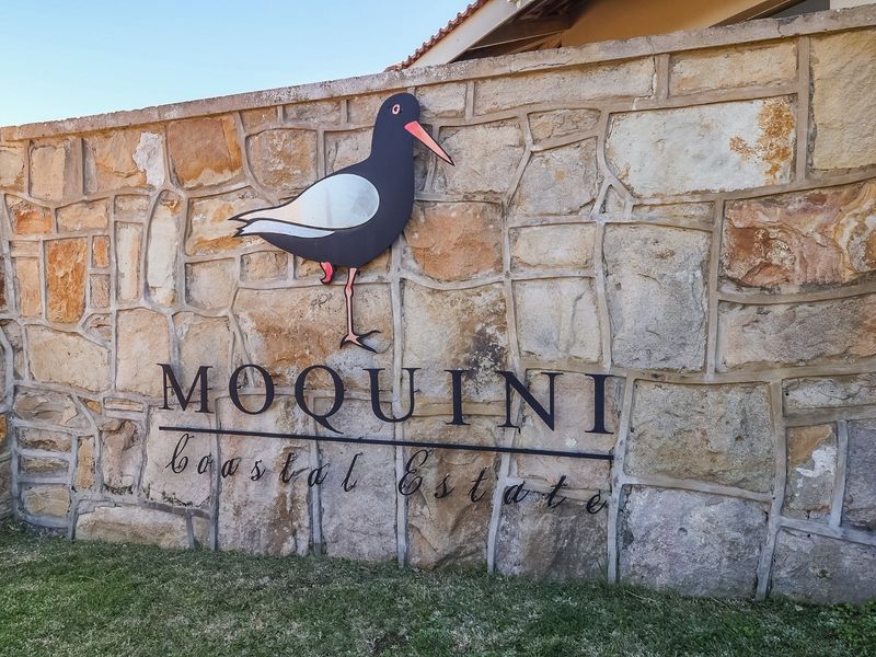 A stone-clad boundary wall featuring the Moquini Coastal Estate signage, marking the entrance to the residential development.