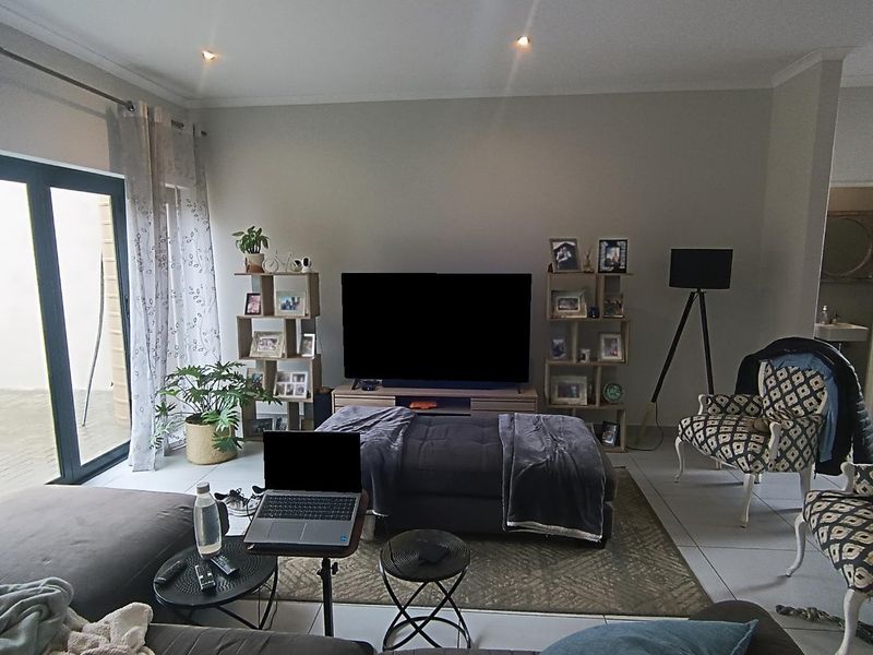Spacious living room featuring large sliding glass doors providing natural light, tiled flooring, and recessed downlighting, with direct access to an adjacent staircase.